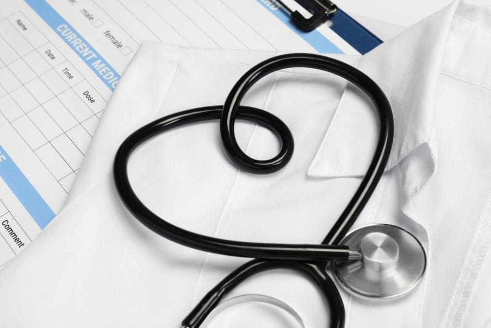 Medical uniform, stethoscope in shape of heart and documents 
