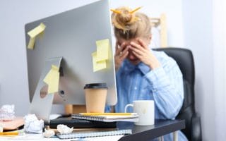 A frustrated employee at her computer looking tired
