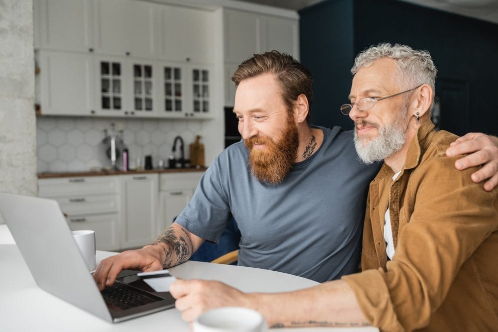Smiling young man working on a laptop with his senior citizen father