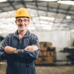 Older worker at a factory with a hard hat on