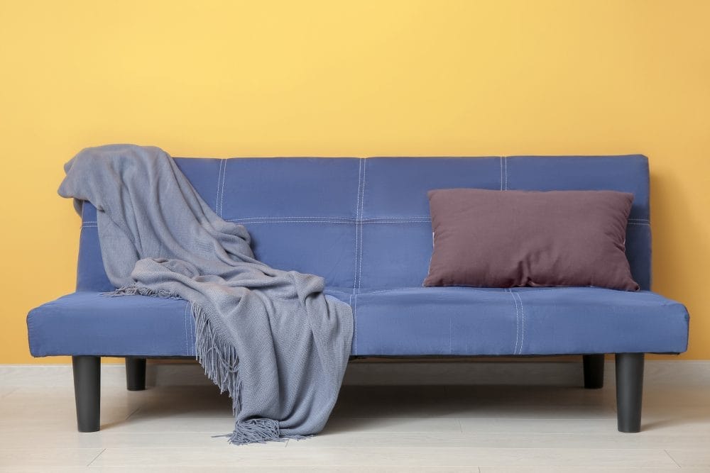 Cheap furniture: an old blue sofa in a yellow room