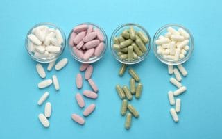 Different vitamin pills on light blue background
