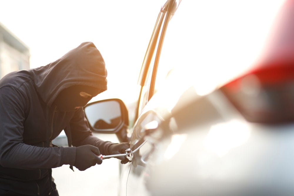 Car thief attempting to break into the door of a parked automobile.