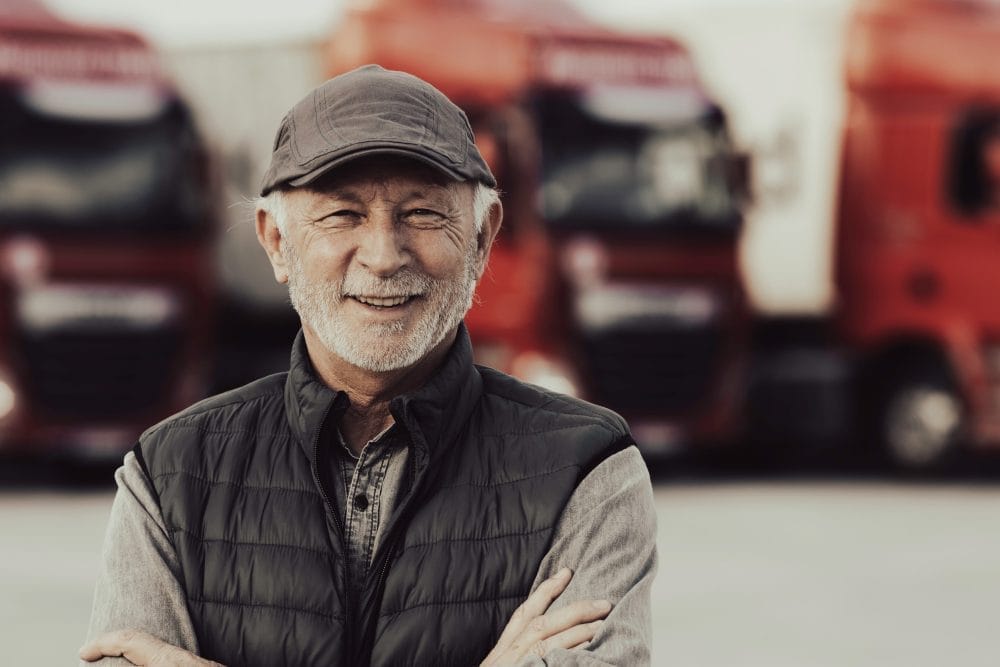Senior man standing in front of trucks