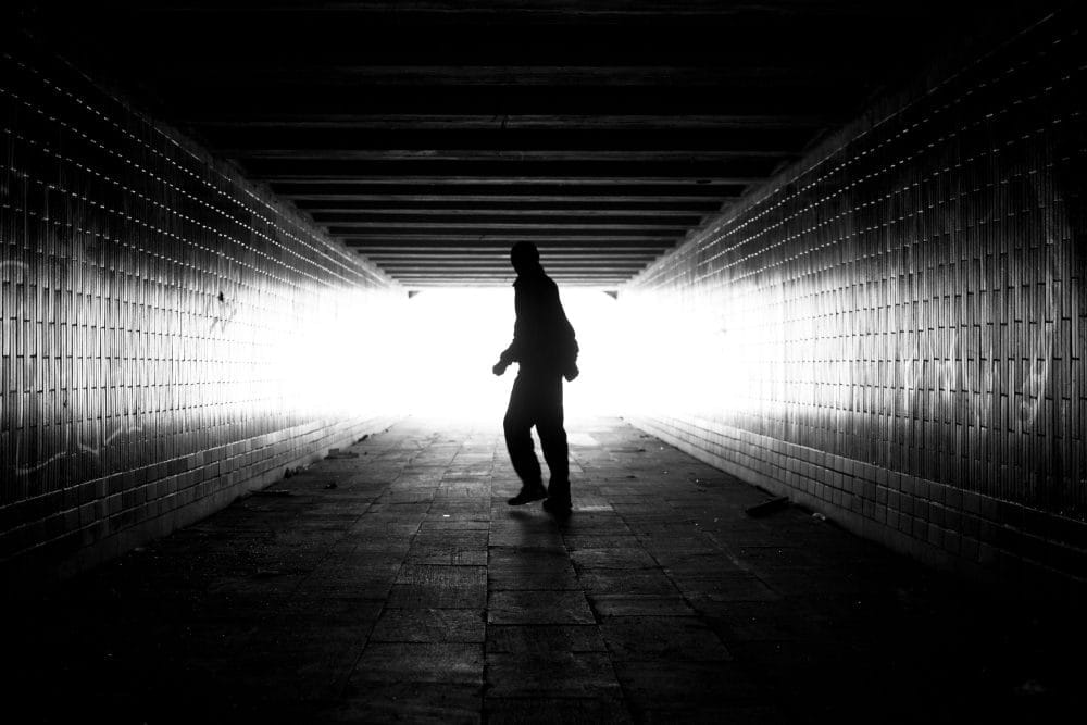 A victim of talking walking down a dark tunnel in black and white