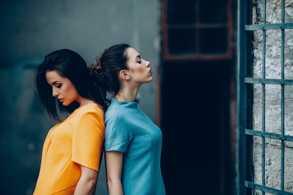 Two young women upset with each other and standing back to back