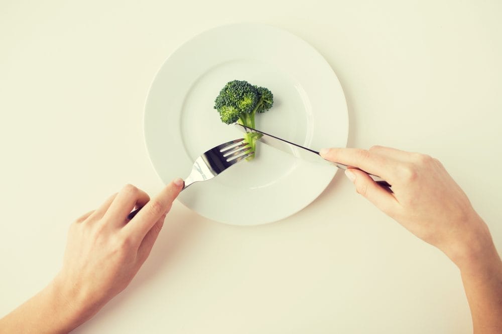 close up of woman hands eating broccoli