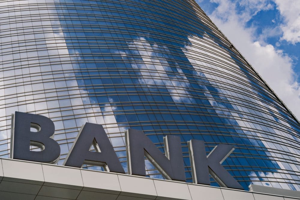 A bank sign outside of a tall building