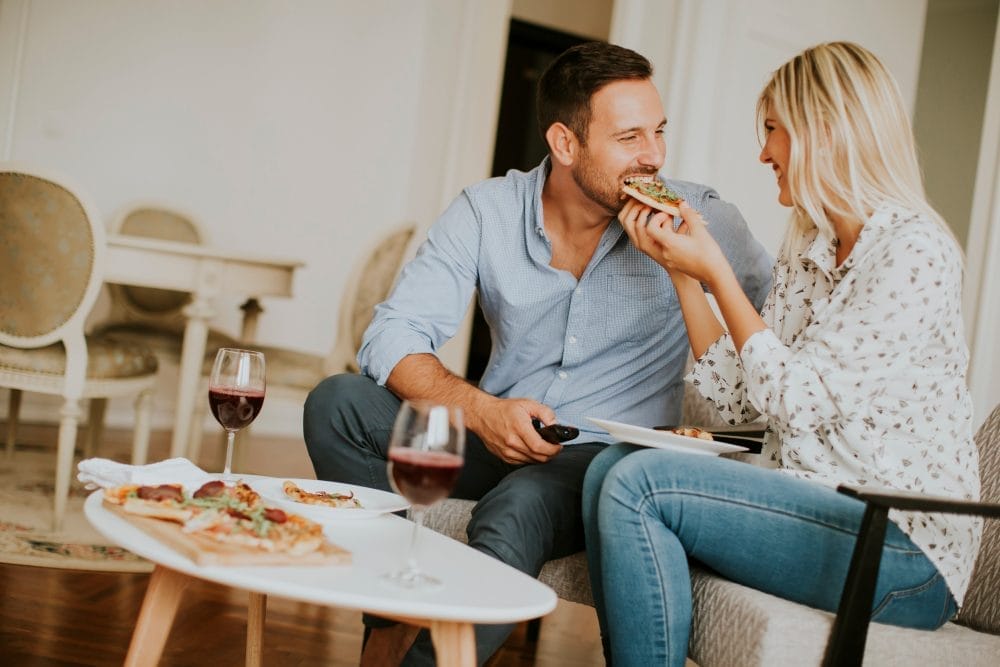 Young couple eating pizza at home