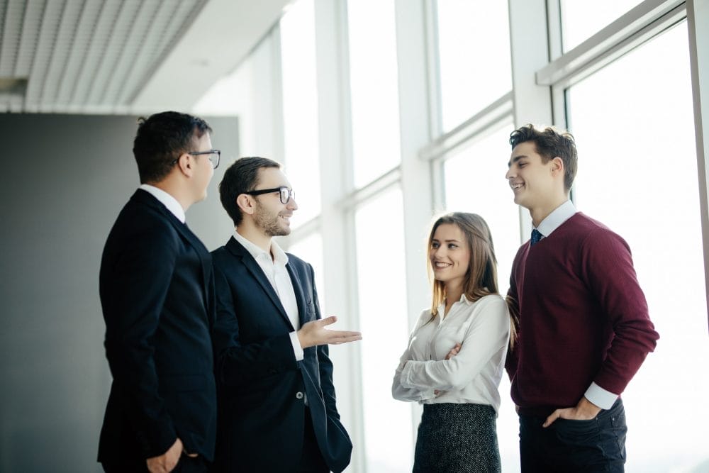 Professional business people standing around in informal group chatting