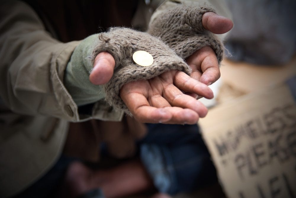 Homeless adult man reaching out for help with change in his hand