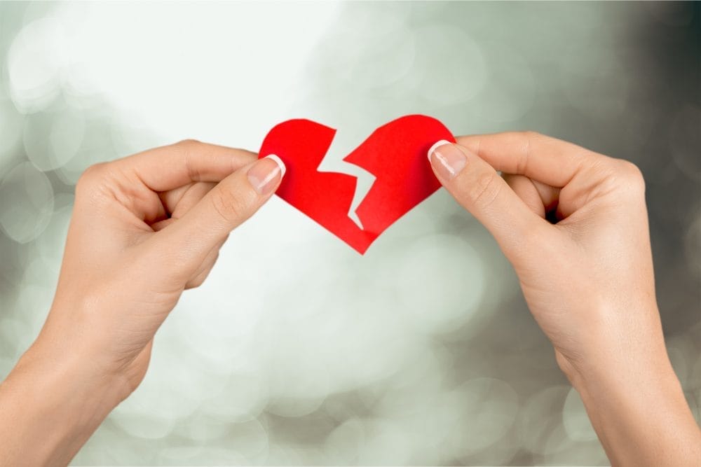 A woman who has been left ripping a paper heart in half