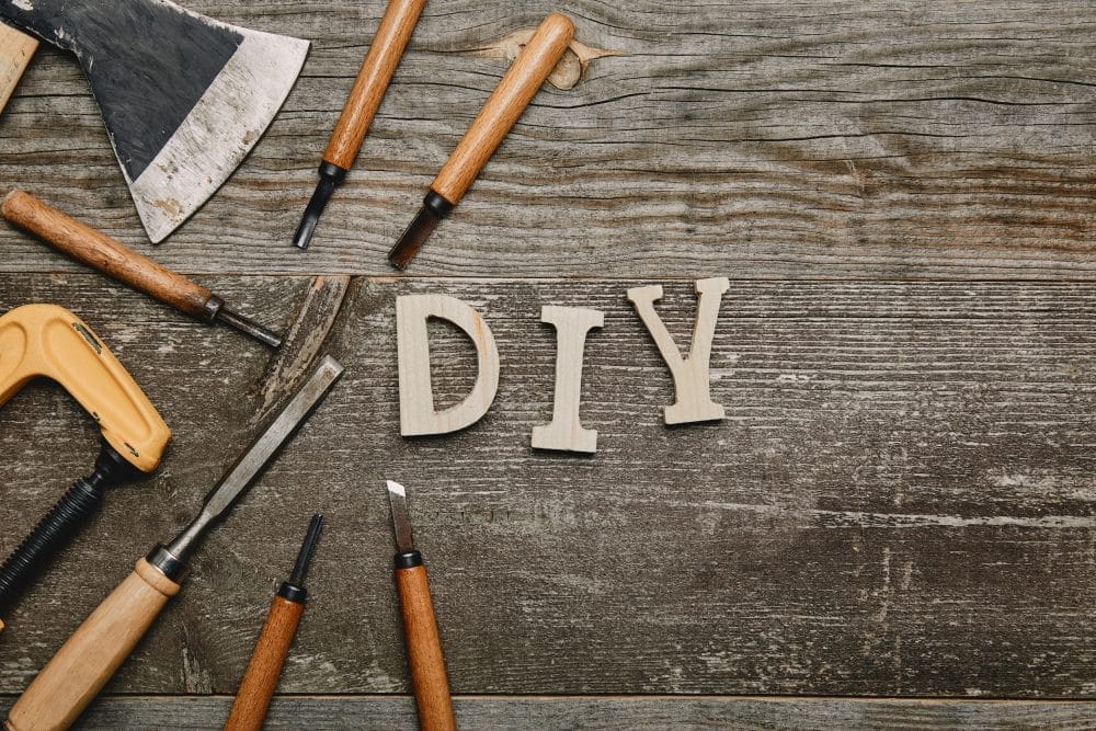 "DIY" written on a wooden table with tools around it