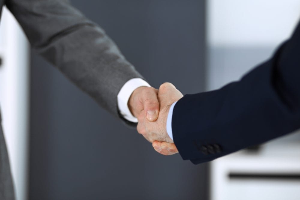 Two people shaking hands, a modern etiquette rule that might actually be offensive