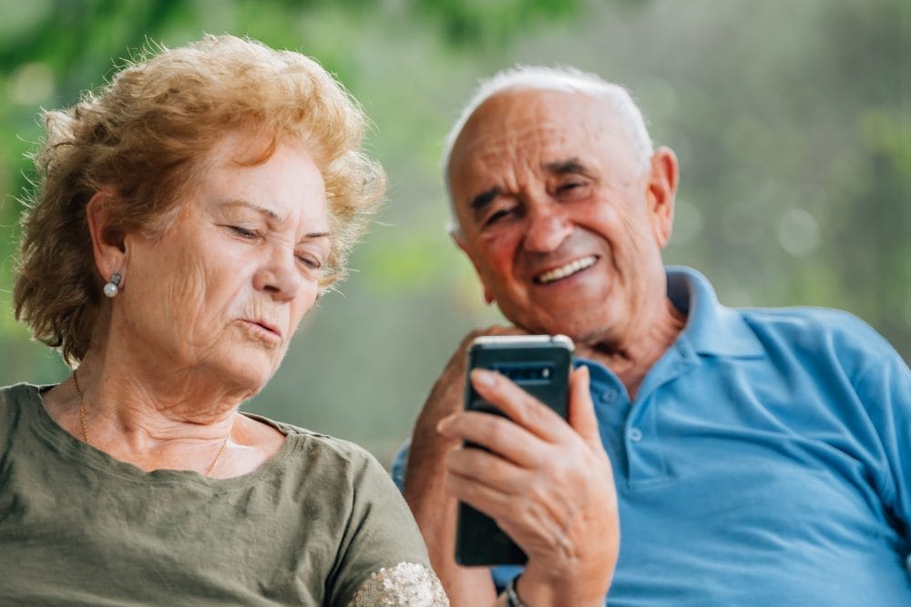 A pair of grandparents using technology to attend a family milestone