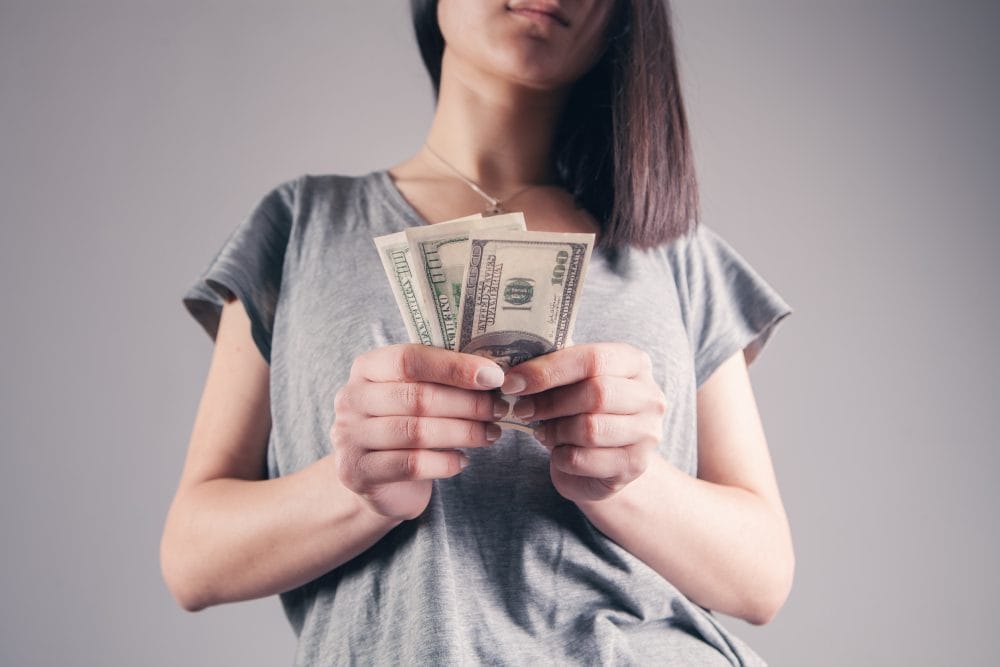 A young woman holding cash that she accepted as financial help from her parents