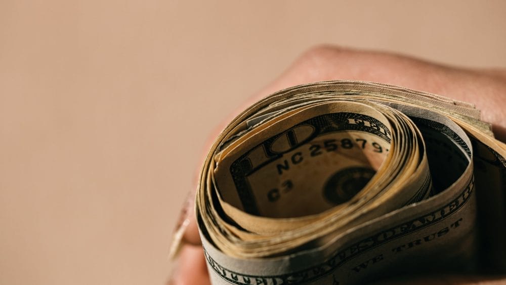 Rolled up American currency, which can lead to a debt for millennials accepting family inheritance