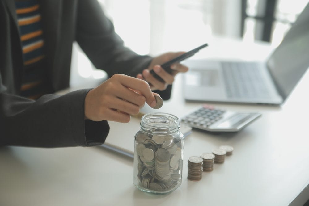 An American dropping coins into a jar, to give them personal finance skills