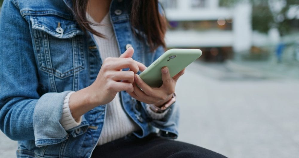 A woman checking her phone, which is a personal habit that people find untrusworthy