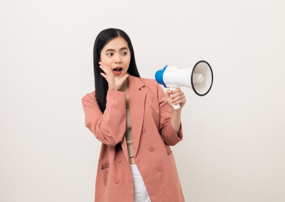 A woman speaking out loud through a megaphone, amplifying her voice