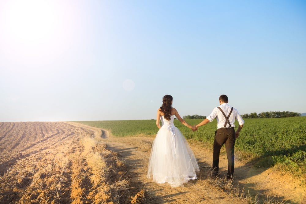 A couple starting their marriage by walking down a dirt road