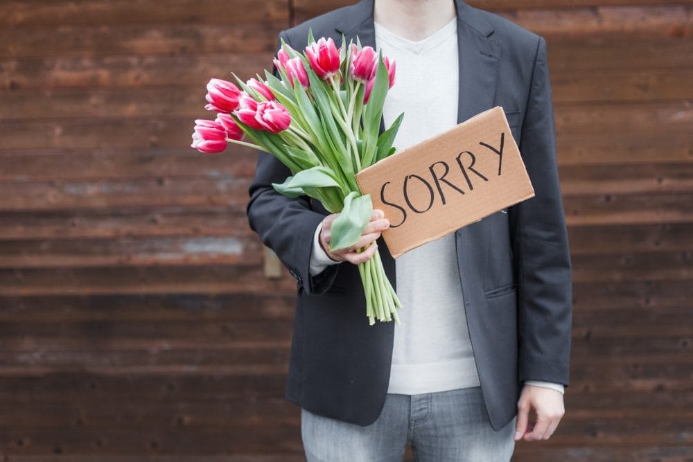 A man with flowers offering one of the apologies that do more harm than good