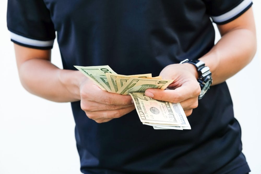 A man holding cash, a budget trick that sounds smart but actually isn't.