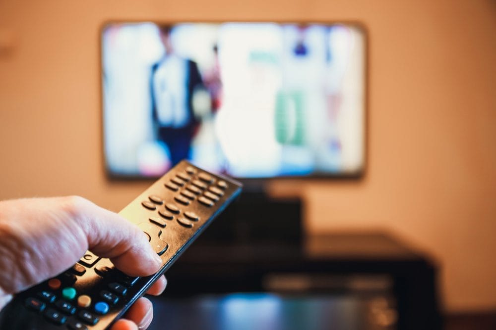 Someone with a remote in front of a television, watching streaming shows