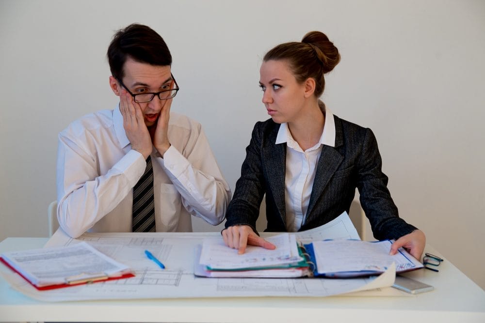 Two businesspeople looking upset, because gossiping hurts morale