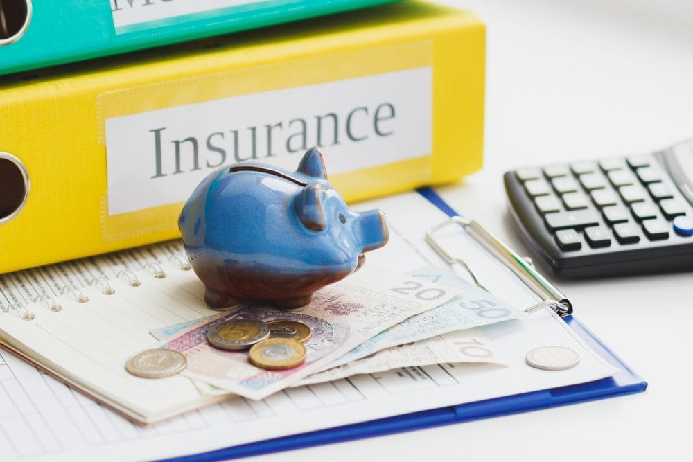 A desk with insurance paperwork and binders. There are types of insurance that are useless these days