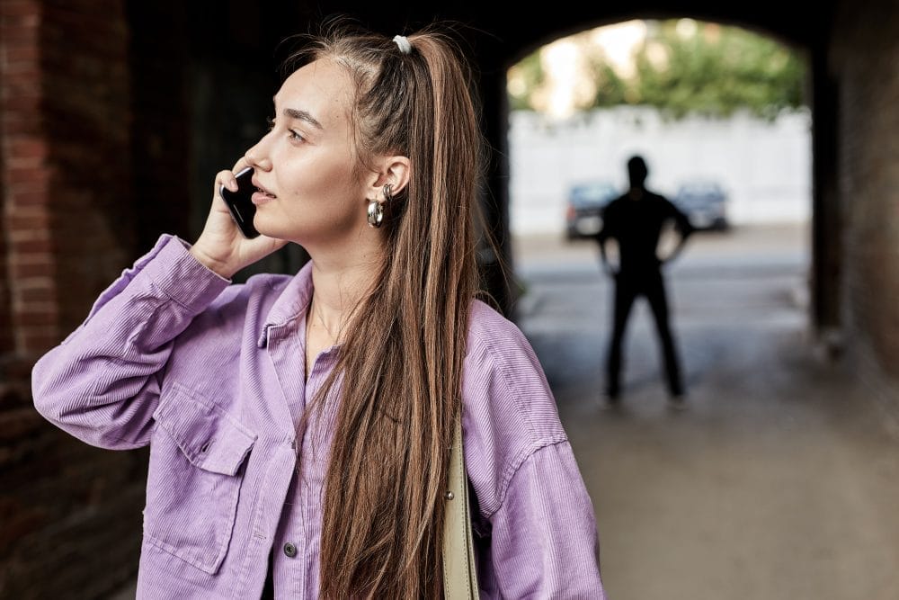 A woman on her phone being followed by a stalker in public