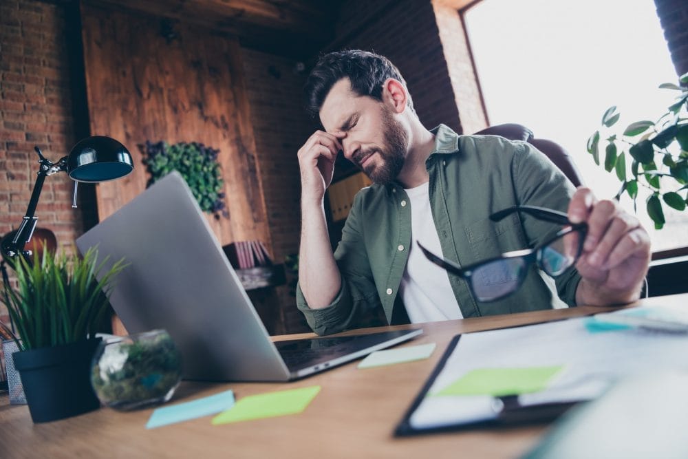 A man looking exhausted and distressed at his workplace