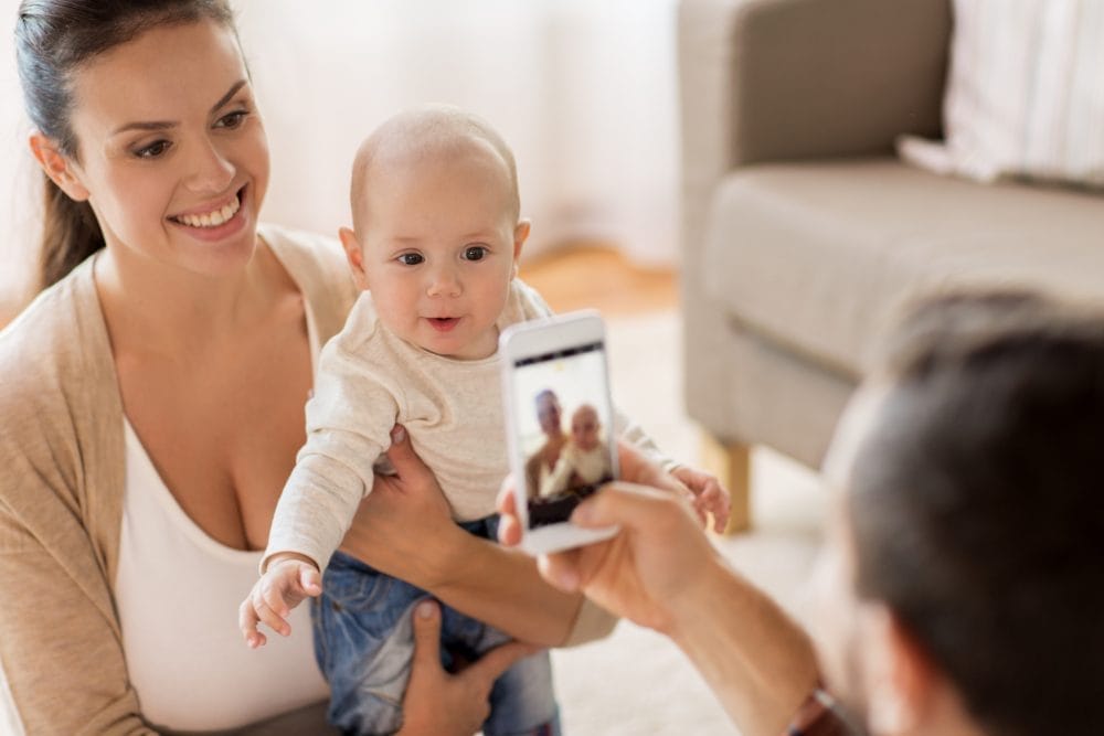 A couple of new parents using a parenting app on their smartphones with a baby